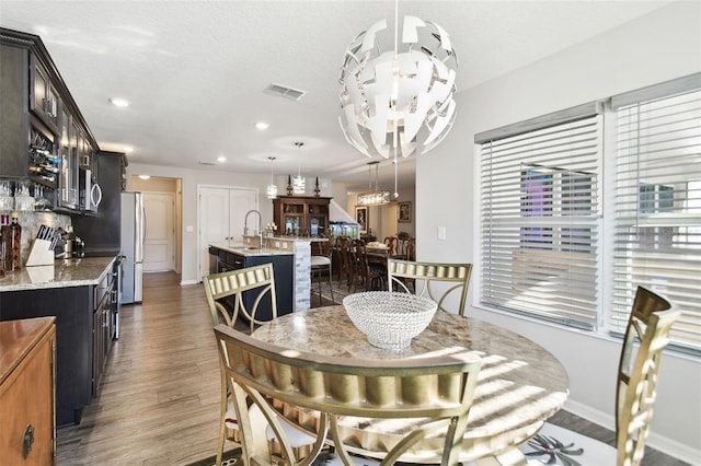 dining area featuring a textured ceiling, dark hardwood / wood-style flooring, a notable chandelier, and sink