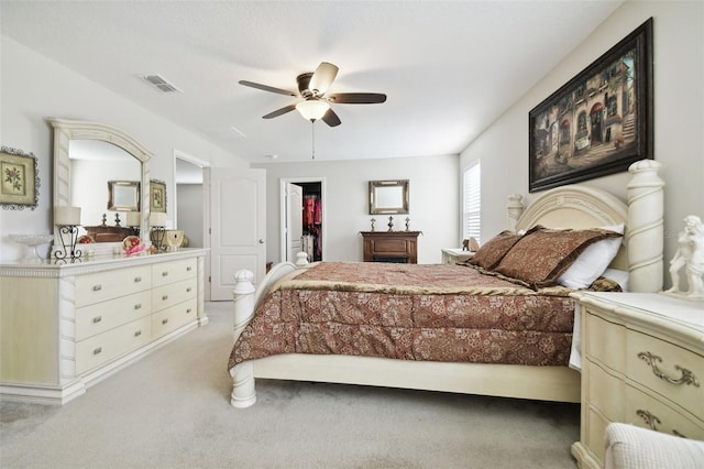 carpeted bedroom with a walk in closet, a closet, and ceiling fan