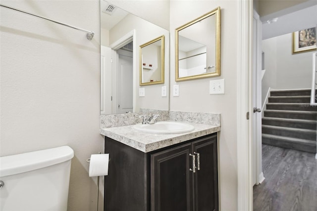 bathroom with wood-type flooring, vanity, and toilet