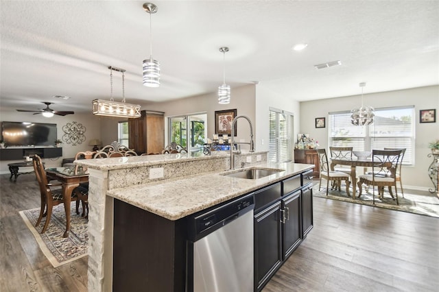 kitchen with a kitchen island with sink, dishwasher, decorative light fixtures, and sink