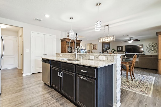 kitchen featuring light wood-type flooring, ceiling fan, decorative light fixtures, a center island with sink, and dishwasher