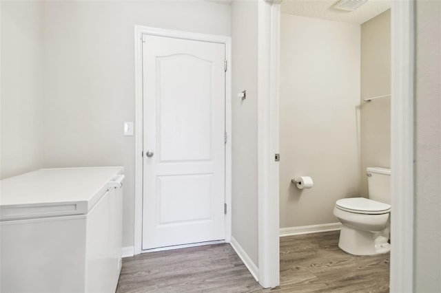 bathroom with wood-type flooring and toilet