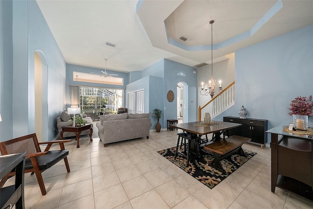 dining space with ceiling fan with notable chandelier and a raised ceiling