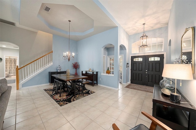 entryway with a notable chandelier, light tile patterned floors, and a tray ceiling