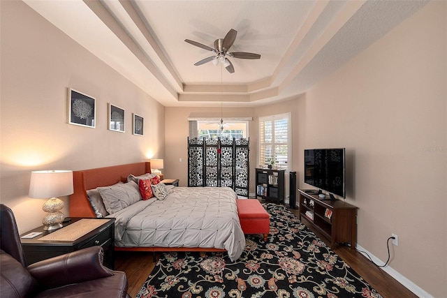 bedroom featuring a raised ceiling, ceiling fan, and dark hardwood / wood-style flooring