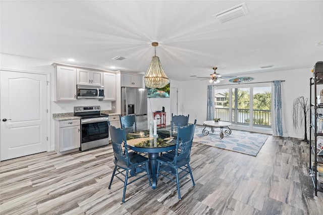 dining area with light hardwood / wood-style flooring and ceiling fan with notable chandelier