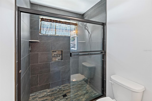 bathroom with a shower with door and toilet