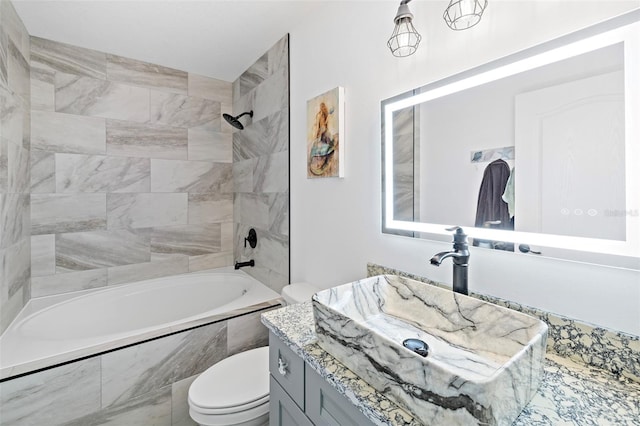 full bathroom featuring vanity, tiled shower / bath combo, and toilet