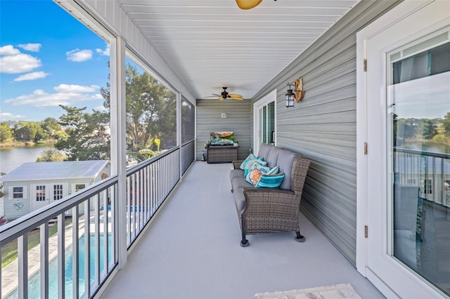 sunroom featuring ceiling fan and a water view