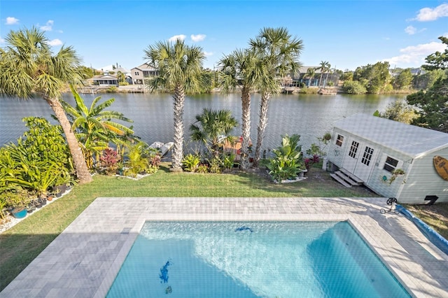 view of swimming pool with an outbuilding, a patio, and a water view