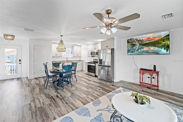 dining area featuring ceiling fan, light hardwood / wood-style floors, and a textured ceiling