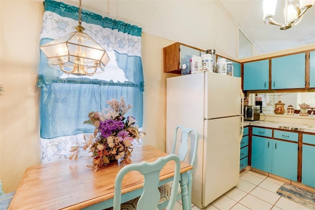 kitchen featuring white fridge, hanging light fixtures, light tile patterned floors, and an inviting chandelier