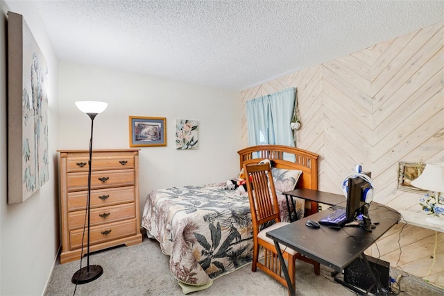 bedroom featuring a textured ceiling, wooden walls, and light carpet