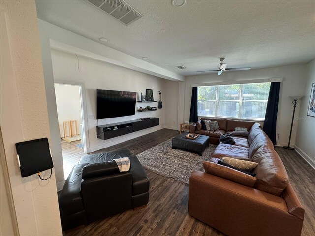 living room with a textured ceiling, dark hardwood / wood-style floors, and ceiling fan