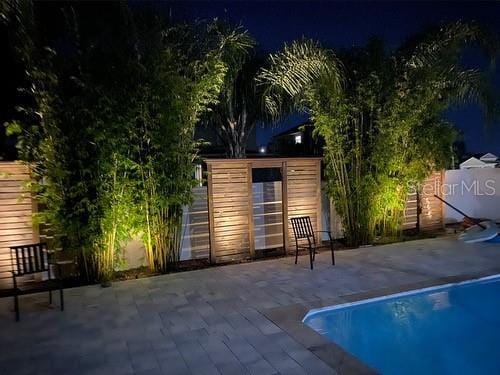 pool at night featuring a patio