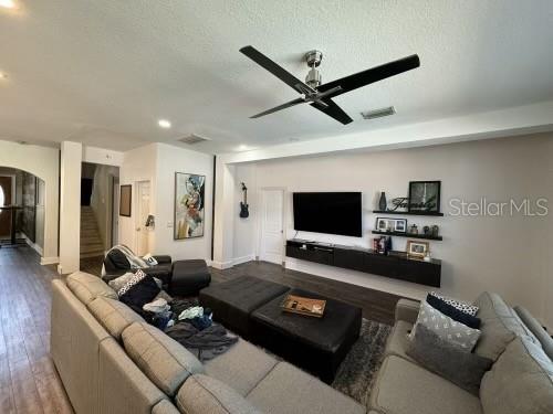 living room with ceiling fan, wood-type flooring, and a textured ceiling