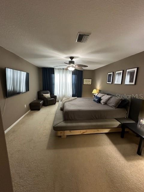 bedroom featuring carpet flooring, ceiling fan, and a textured ceiling