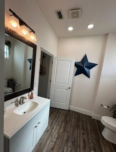 bathroom featuring vanity, wood-type flooring, and toilet