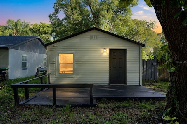 back house at dusk featuring a deck