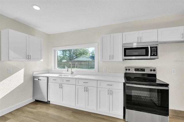 kitchen featuring sink, white cabinets, light wood-type flooring, and appliances with stainless steel finishes