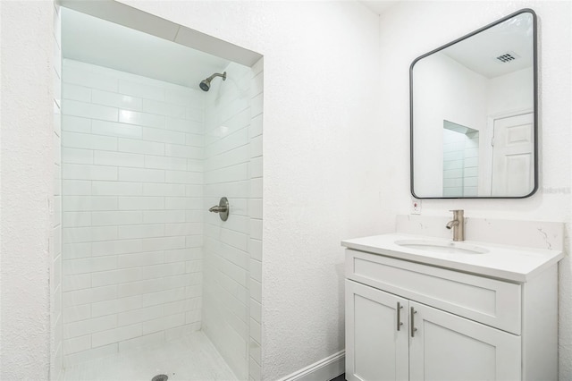 bathroom with a tile shower and vanity