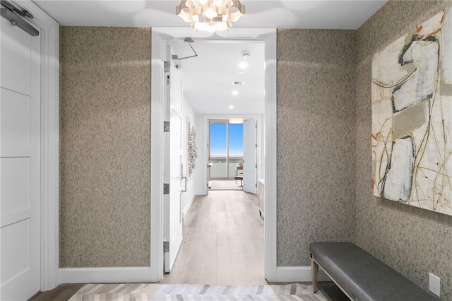 hall with light hardwood / wood-style flooring and a notable chandelier