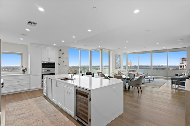 kitchen featuring white cabinets, light wood-type flooring, wine cooler, and sink