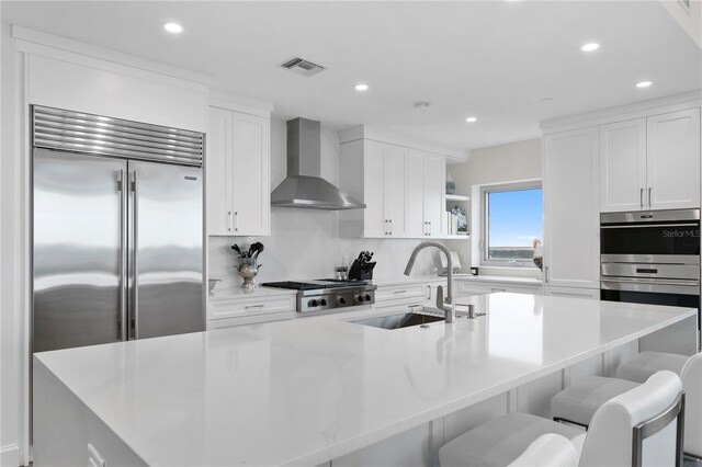 kitchen featuring a large island, sink, wall chimney exhaust hood, and stainless steel appliances