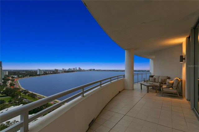 balcony at dusk featuring outdoor lounge area and a water view