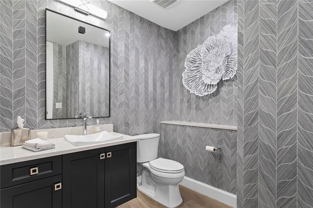 bathroom with hardwood / wood-style flooring, vanity, and toilet