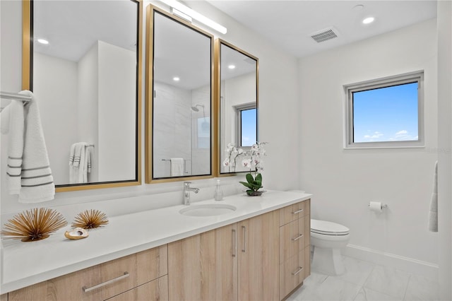 bathroom featuring vanity, toilet, and a tile shower