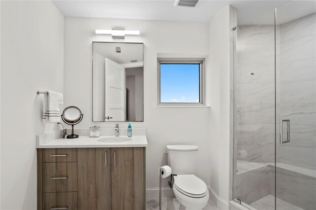 bathroom with vanity, a shower with shower door, and toilet