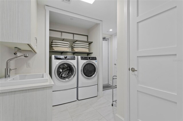 laundry area featuring washer and dryer, cabinets, and sink