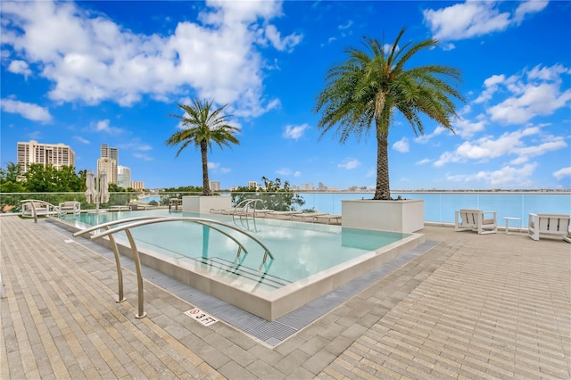 view of pool featuring a water view and a patio