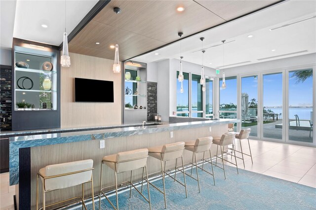 bar featuring light tile patterned floors, a healthy amount of sunlight, and decorative light fixtures