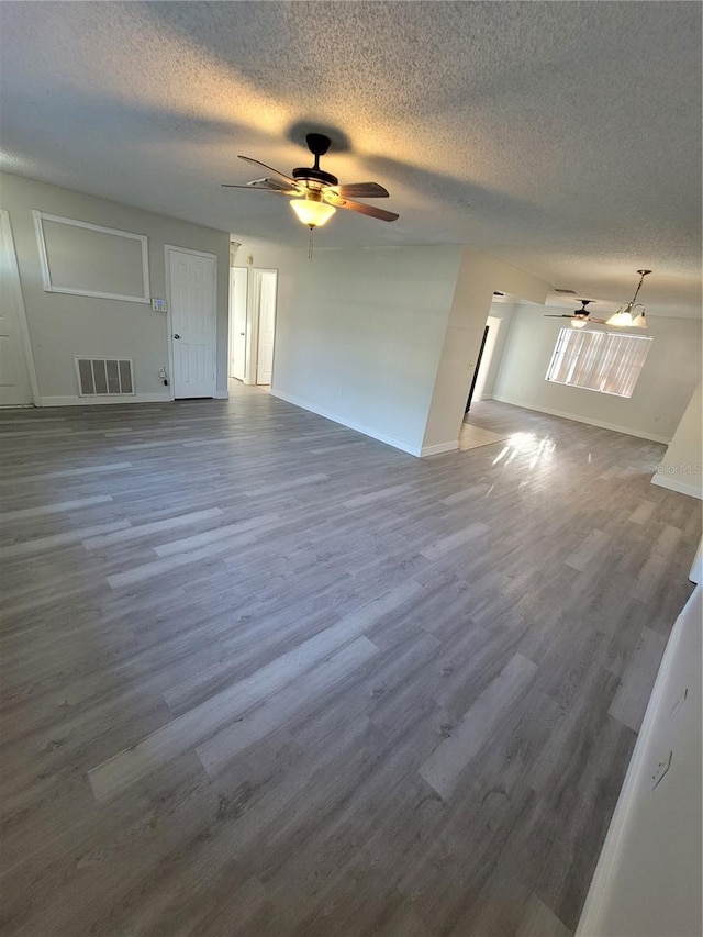 empty room with a textured ceiling, dark hardwood / wood-style floors, and ceiling fan