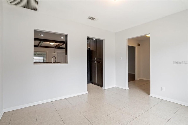 tiled spare room with beam ceiling