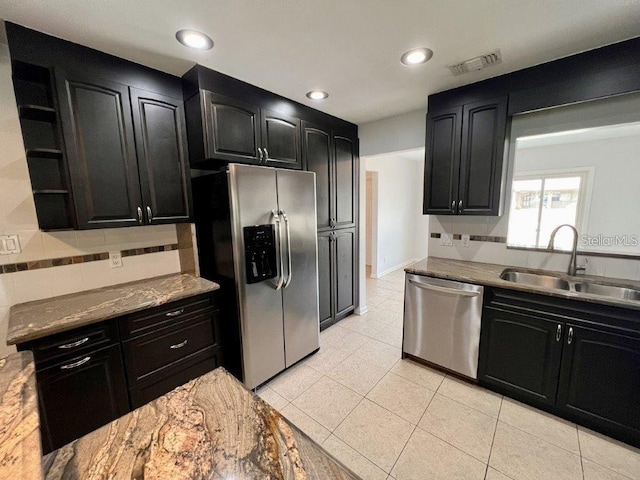 kitchen with light stone countertops, sink, decorative backsplash, light tile patterned floors, and appliances with stainless steel finishes