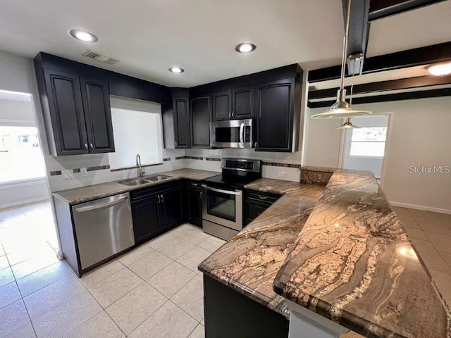 kitchen with sink, stainless steel appliances, kitchen peninsula, dark stone countertops, and decorative light fixtures