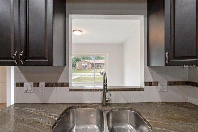 kitchen featuring backsplash, dark brown cabinetry, and sink