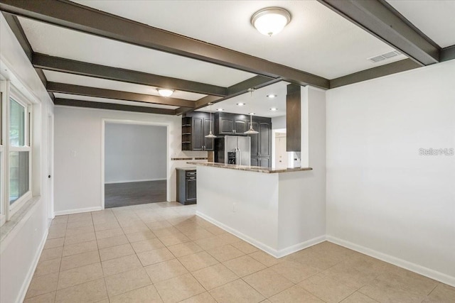 kitchen featuring beamed ceiling, stainless steel fridge, kitchen peninsula, and light tile patterned floors