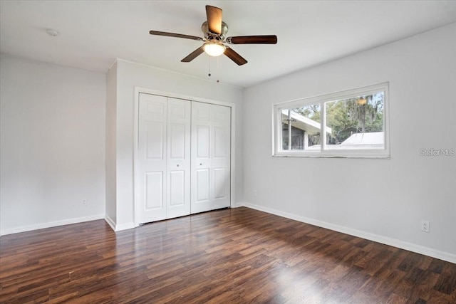 unfurnished bedroom with ceiling fan, a closet, and dark wood-type flooring