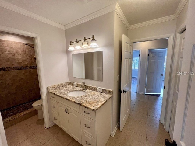 bathroom with tile patterned floors, a tile shower, vanity, crown molding, and toilet