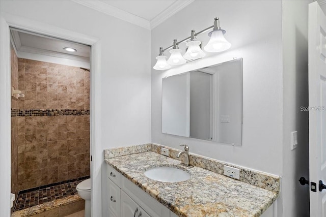 bathroom with a tile shower, vanity, ornamental molding, and toilet