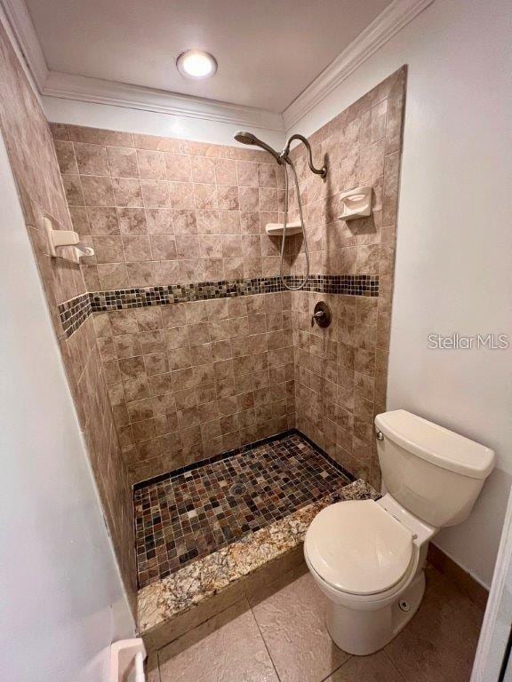 bathroom featuring tiled shower, tile patterned floors, toilet, and ornamental molding