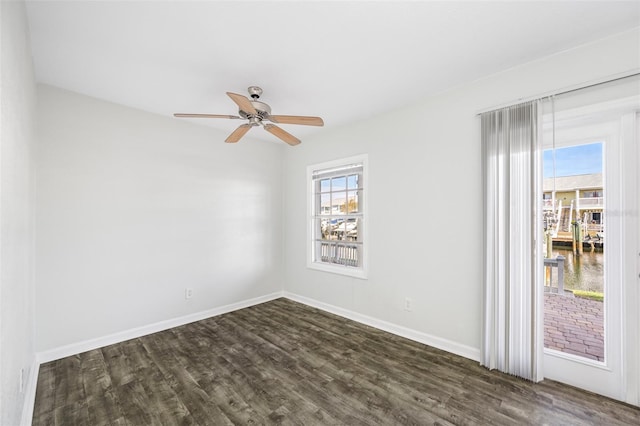 unfurnished room with ceiling fan, a water view, and dark hardwood / wood-style floors