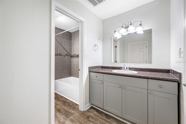 bathroom featuring wood-type flooring, vanity, and tiled shower / bath