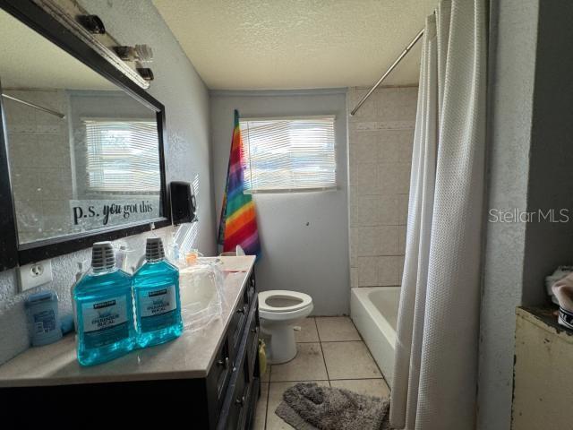 full bathroom with plenty of natural light, vanity, shower / bath combination with curtain, and tile patterned flooring