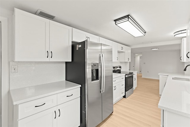 kitchen featuring sink, white cabinets, light hardwood / wood-style flooring, and appliances with stainless steel finishes