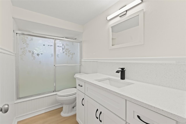 full bathroom featuring wood-type flooring, vanity, toilet, and enclosed tub / shower combo